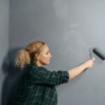 Person streicht eine Bürowand mit einer Farbrolle