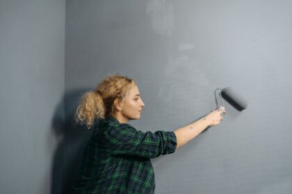 Person streicht eine Bürowand mit einer Farbrolle